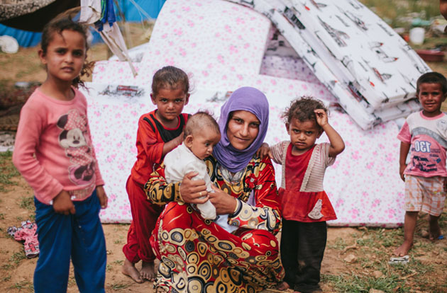Middle Eastern mother and children stand in European refugee camp