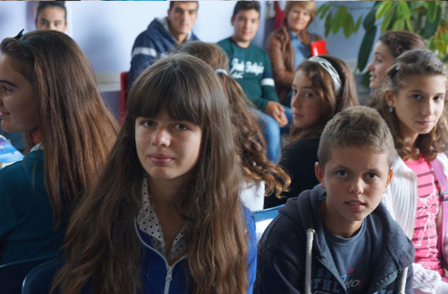 Children and teens sit together in a classroom