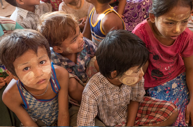 Southeast Asian children with face paint sit on floor