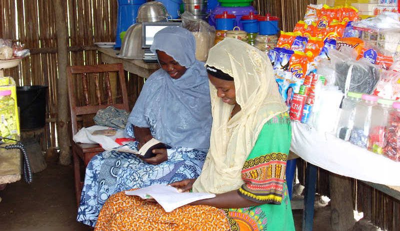 Two Togolese women with head coverings on sitting and reading the bible together