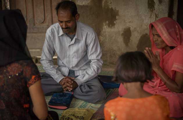 Christian missionary sits in circle and prays with other believers