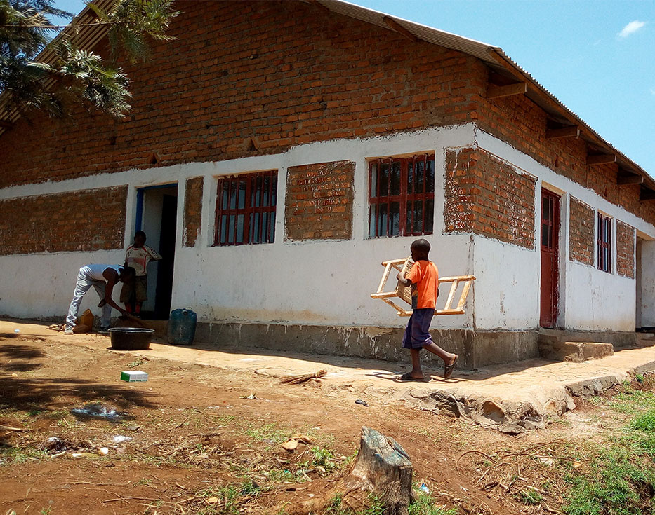 Congolese man and two boys working on a brick building