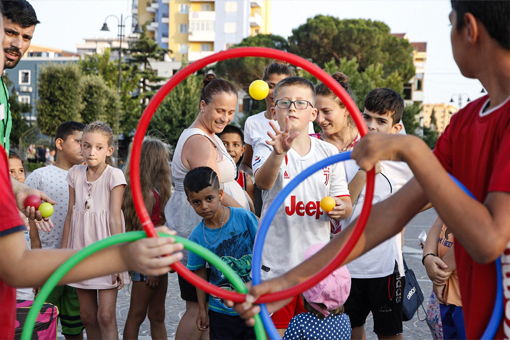 Kids in a line throwing balls through hula hoops