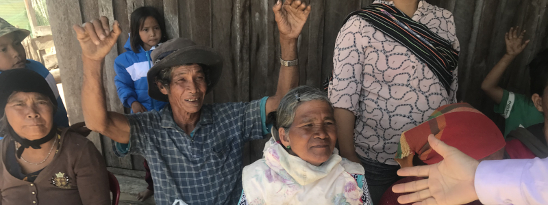 Christian missionary extends his hand to Vietnamese woman while others watch