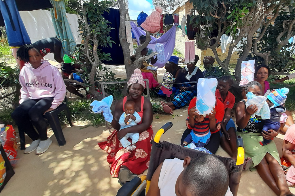 Tanzanian women sit on the ground with their babies in their laps