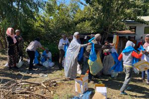 Ethiopian men and women take blue t-shirts from cardboard boxes and grocery bags