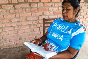 Argentinian woman sits in wooden chair reading the Bible