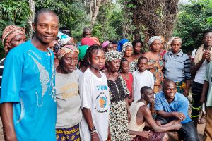 Ivorian men and women posing for a picture in front of a green trees