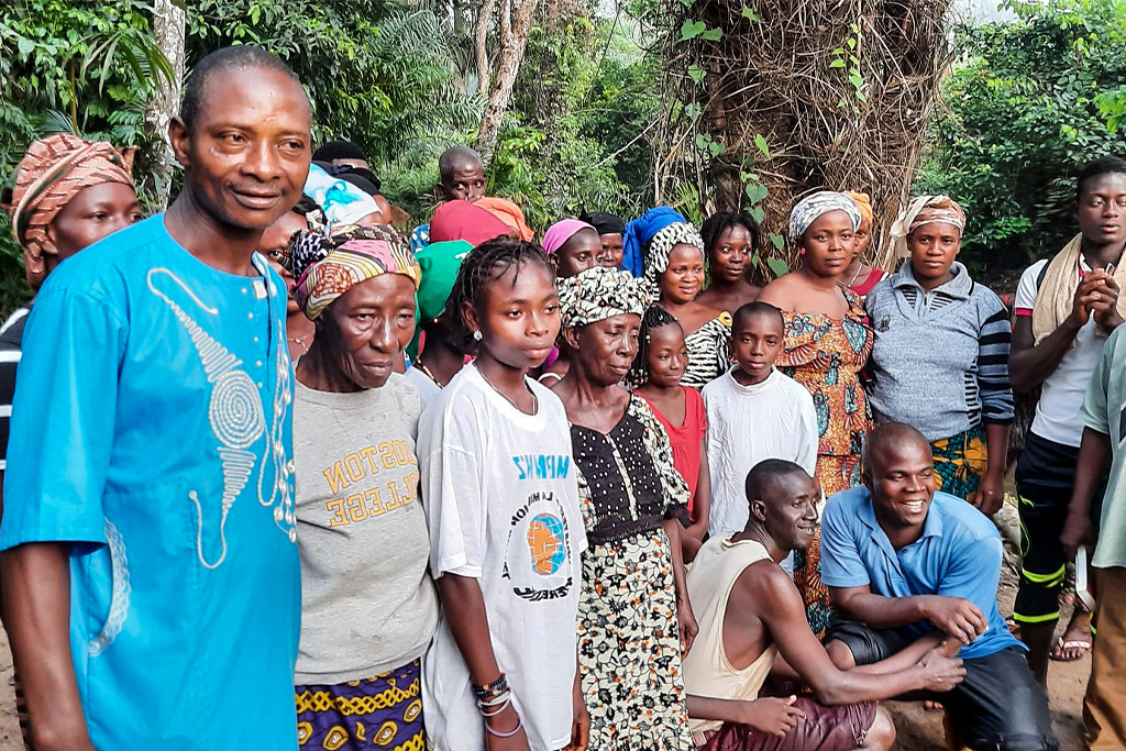 Ivorian men and women posing for a picture in front of a green trees