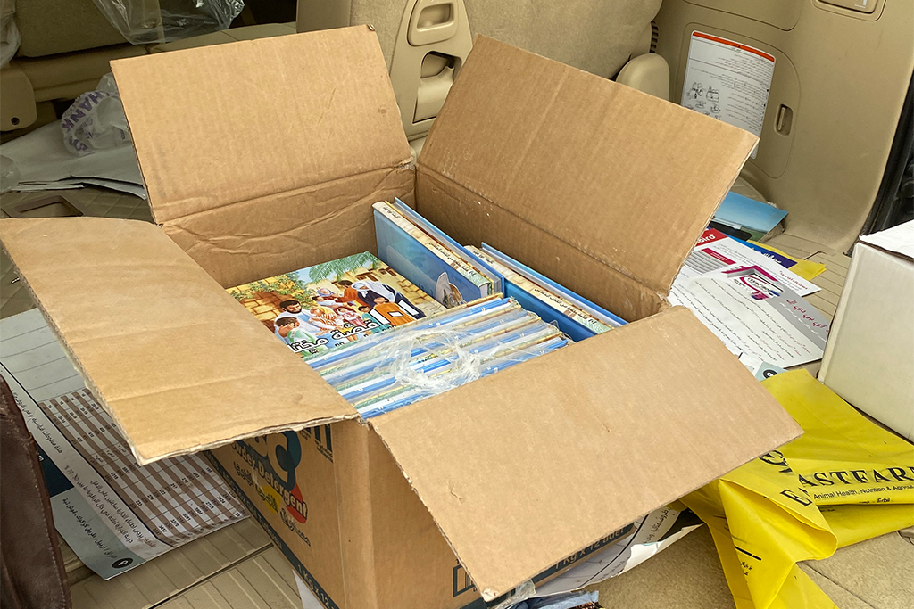 An open cardboard box full of children's picture Bibles written in Arabic