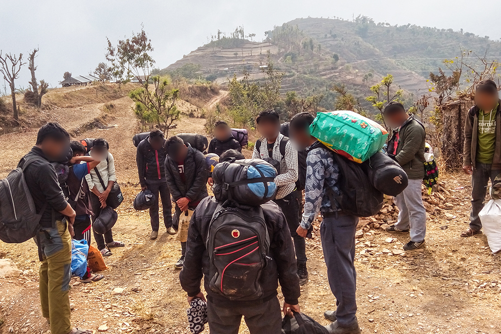 A group of Nepalese Christian men taking a break and praying while hiking through the mountains