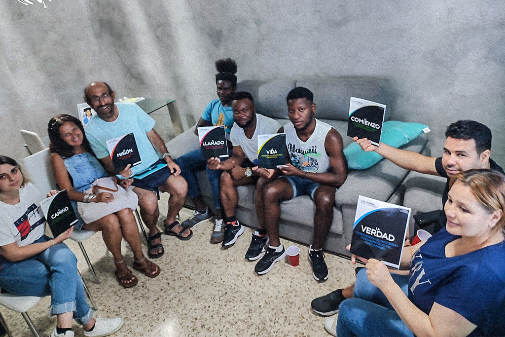 Christian of different ethnicity sit in a circle holding Christian books written in Spanish