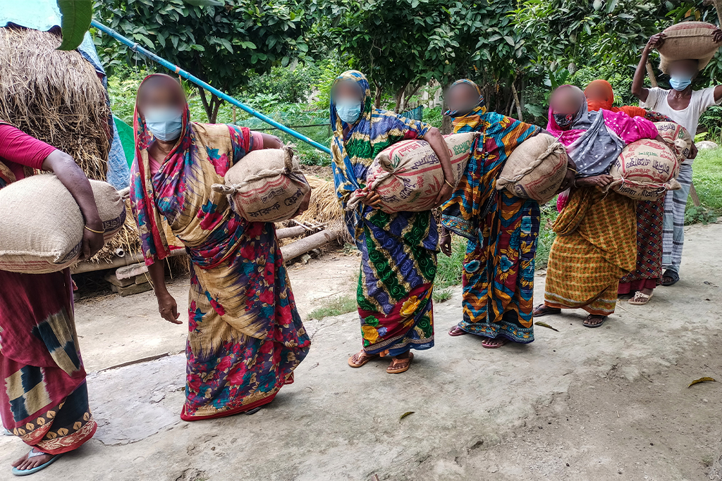 Bangladeshi women carry bags of food under their arm
