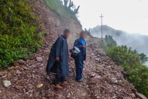 Two Nepalese Christian men walking on a rocky road on the side of a steep mountain