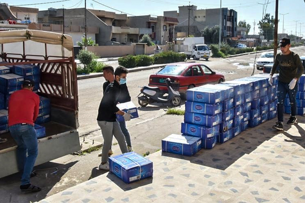 Iraqi Christian men unload truck full of essential items onto sidewalk