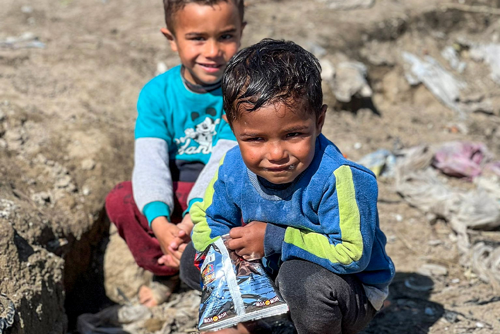 Turkish boy eats from a snack bag in a refugee camp