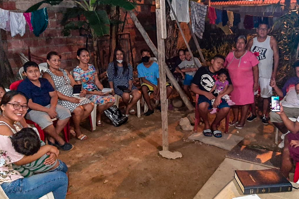 Ecuadorian Christians sitting outside in a circle in plastic yard chairs holding their Bibles
