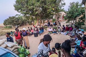 Zimbabweans sitting in a semicircle waiting for workers to deliver essential food items