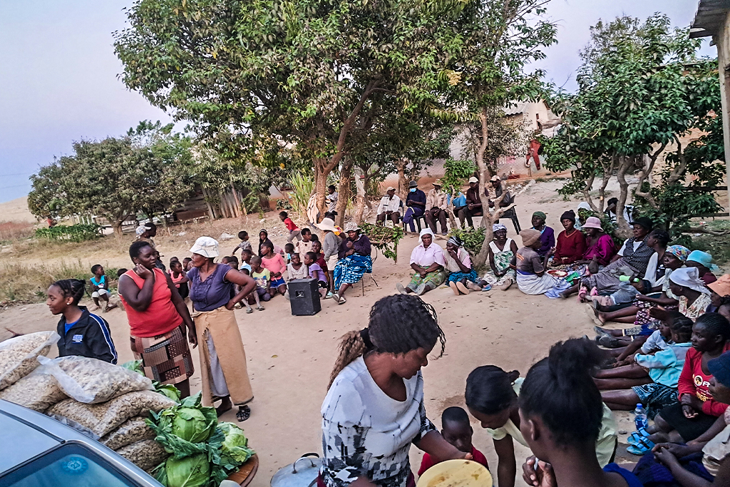 Zimbabweans sitting in a semicircle waiting for workers to deliver essential food items