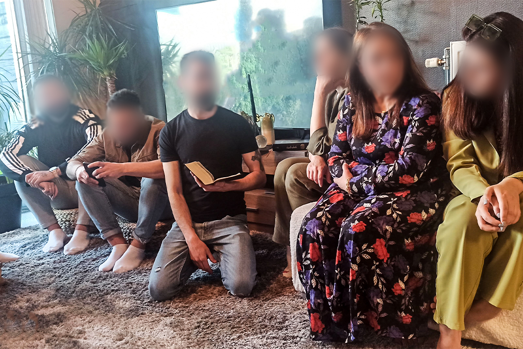 Refugees in Greece gather on a carpeted floor for a bible study