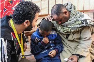 Two men and a boy sitting on a bench praying together