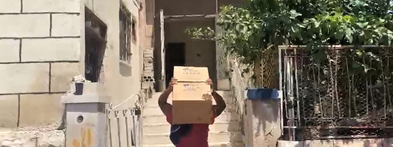 Jordanian man carrying a cardboard box on his head walking up concrete steps