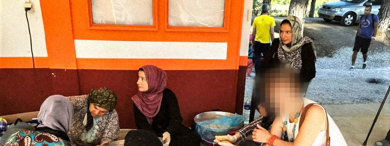 Middle Eastern refugees sit on the sidewalk in Greece