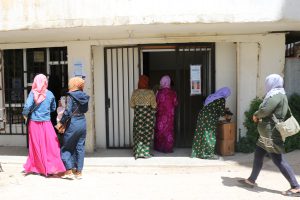 Two Lebanese women walk into a store while other Lebanese women walk down the street