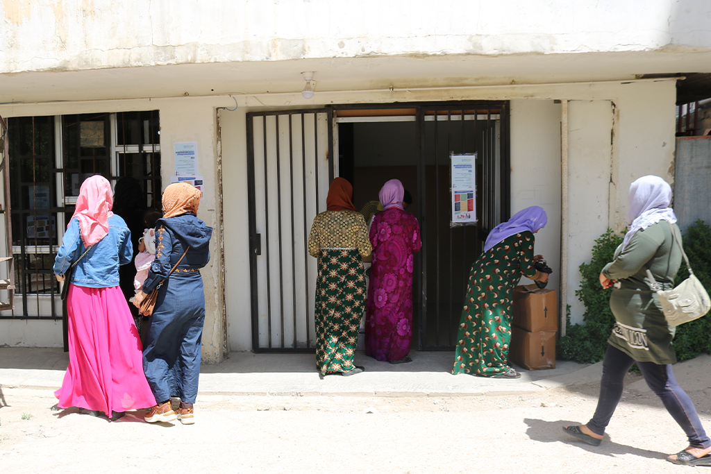 Two Lebanese women walk into a store while other Lebanese women walk down the street
