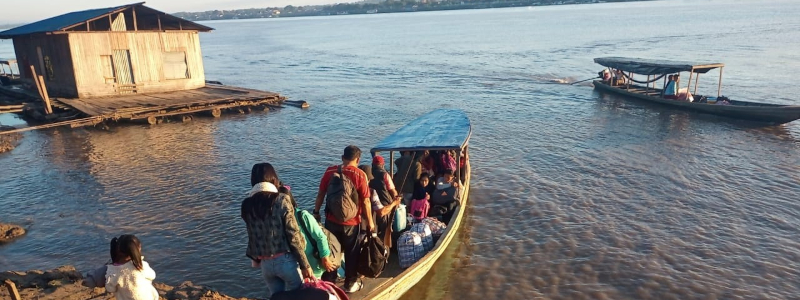 Peruvians board a small wooden boat on a river