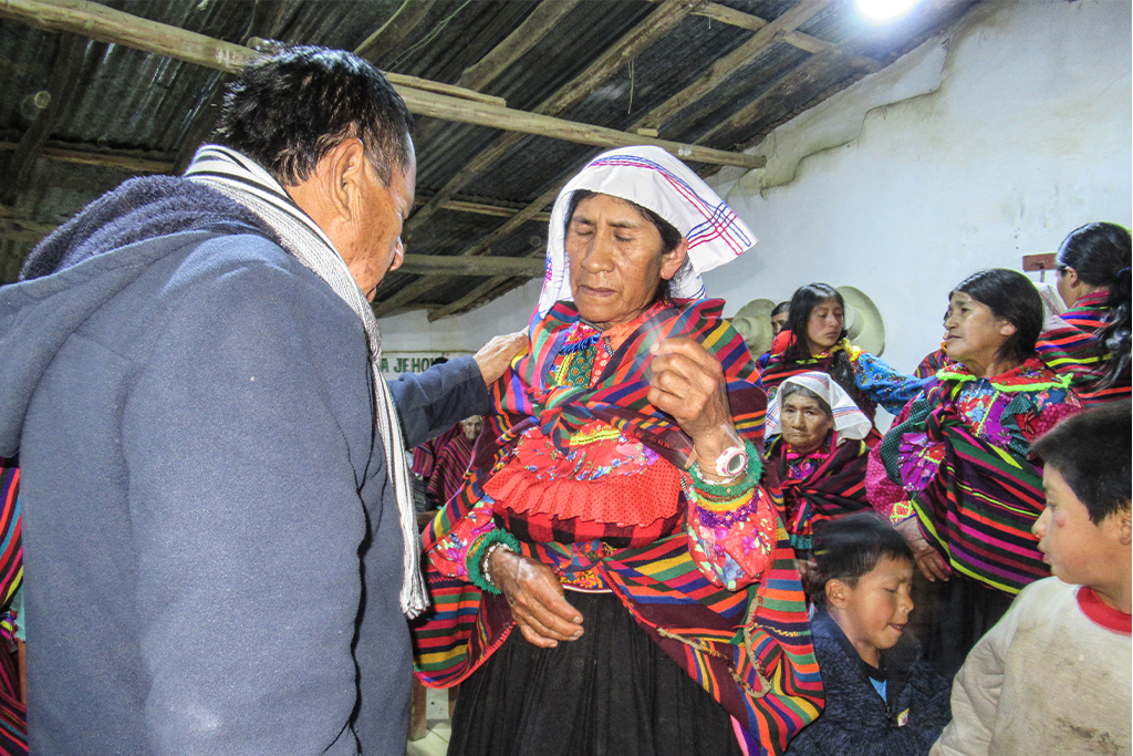 Christian missionary puts his hand on woman's shoulder while praying with her
