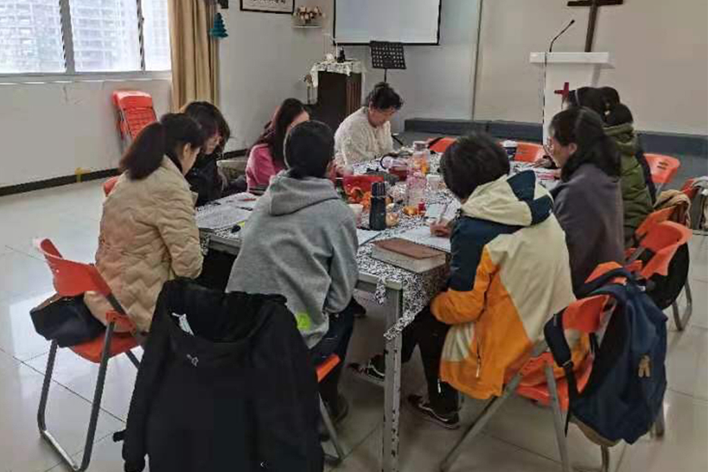 Chinese Christian women sit in orange chairs around a table for a Bible study