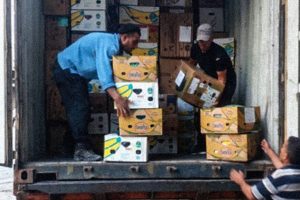 Lebanese men unloading packages of clothes from a shipping truck