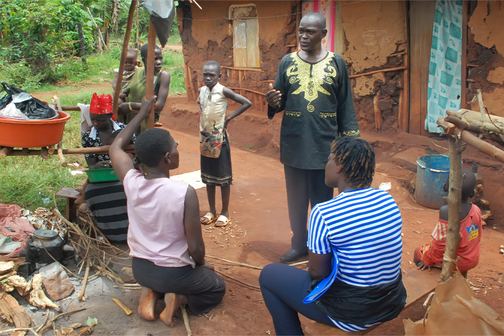 Ugandan father talking to his oldest children while his wife and younger children stand behind him
