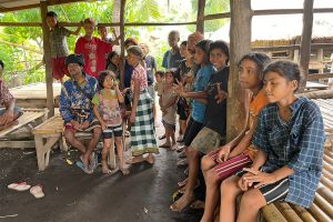 Indonesian girls sitting on bamboo benches under a pavilion made from wooden beams