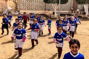African children running outside in their blue and white soccer uniforms