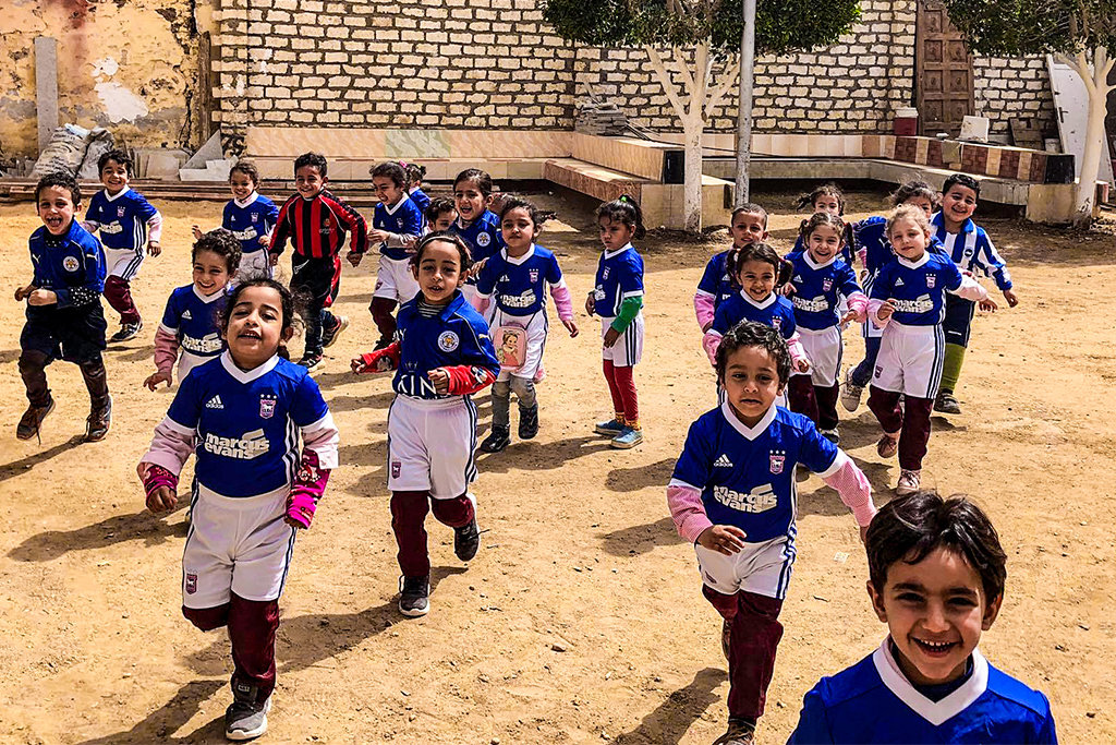 African children running outside in their blue and white soccer uniforms