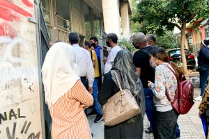 Refugees in Greece wearing masks waiting outside of a government building