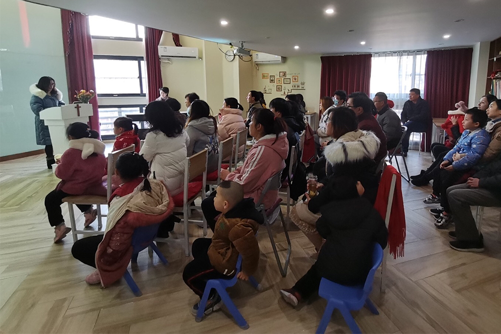 Chinese Christian woman in a winter coat shares her testimony to her church