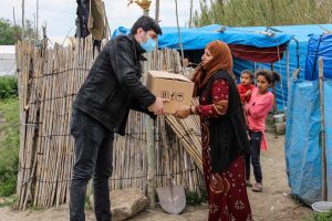 Syrian refugee woman receives a cardboard box full of goods from Christian worker