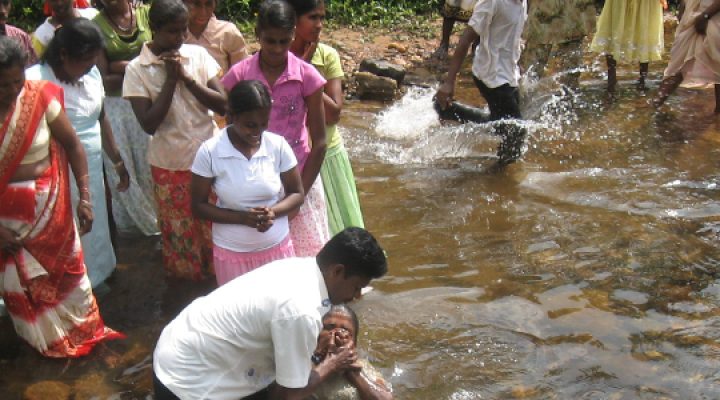 Sri Lankan woman baptized in river by Christian missionary while others watch