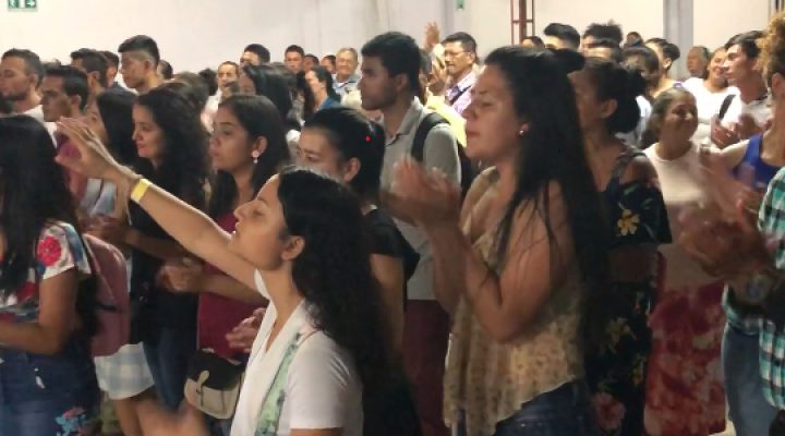 Colombian Christians standing together some with their eyes closed worshiping God