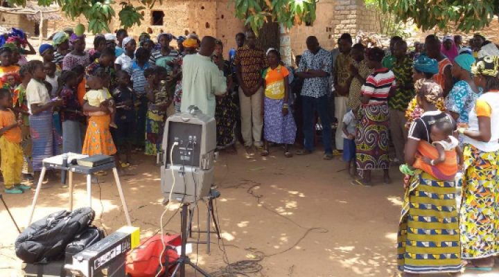 Burkinabé pastor preaches outside in a dusty climate to a group of Christians