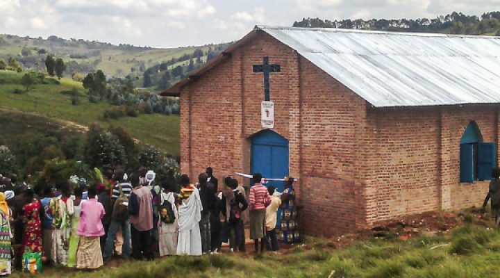 Burundian Christians stand in front of their church looking at the hillside