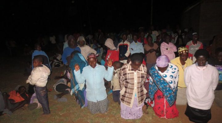 Ghanaian Christians kneeling together on the ground praying and worshiping God