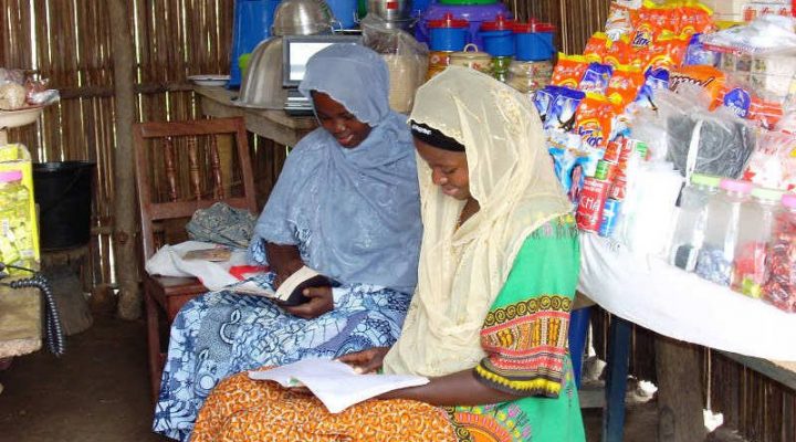 Two Togolese women with head coverings on sitting and reading the bible together