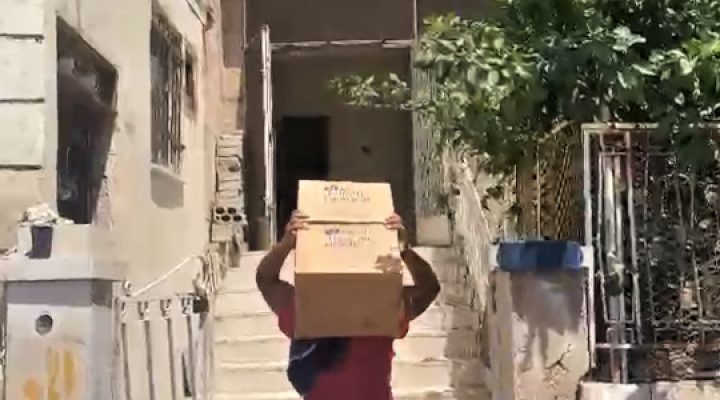 Jordanian man carrying a cardboard box on his head walking up concrete steps